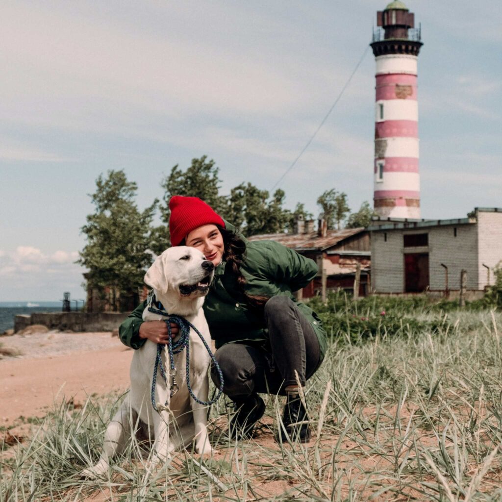 Une femme et son labrador devant un phare