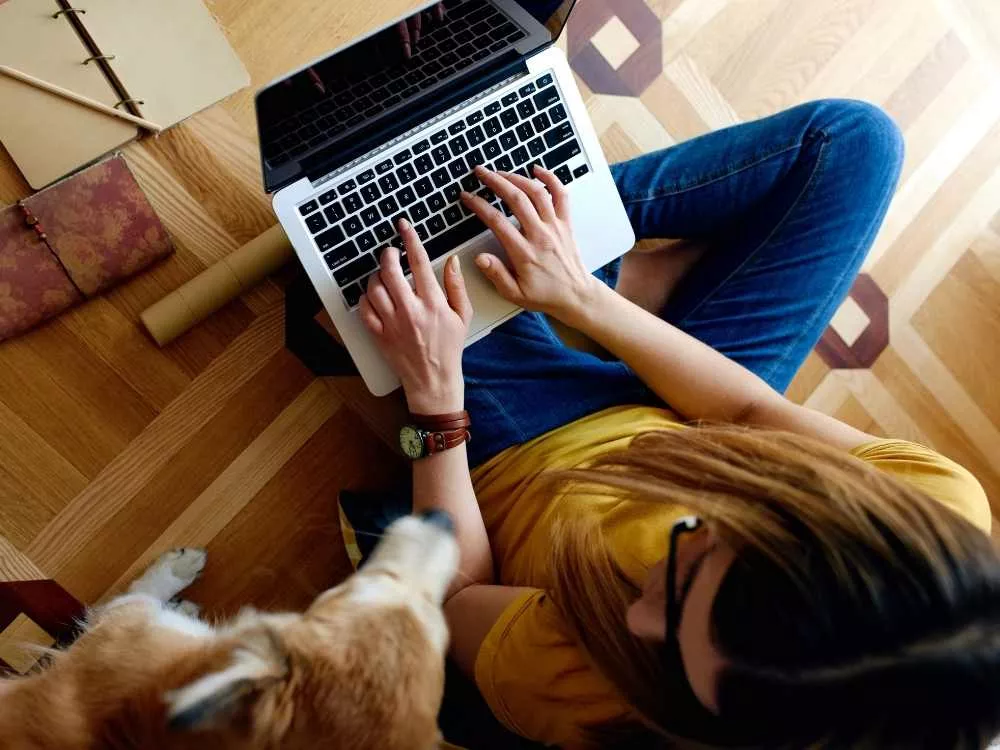 Une femme est son chien au sol avec un ordinateur